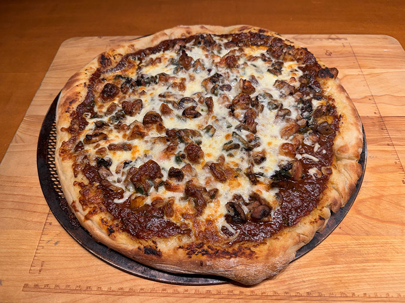 This pizza features chicken, shrimp, mushrooms, and olives.